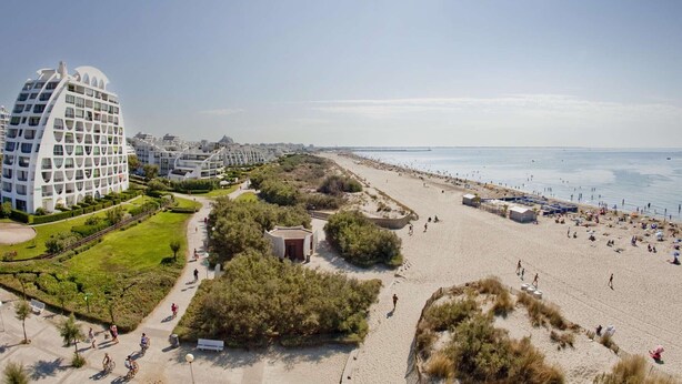 Un hotel costero de diseño moderno, una playa y un cielo despejado.