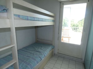 A bunk bed room with a door leading to an outdoor area. - Studio cabin with pool, air conditioning, garage, 300m from beach (La Grande-Motte)