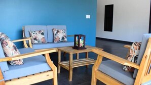 Un rincón con asientos, pared azul, muebles de madera y una pequeña mesa con un adorno.