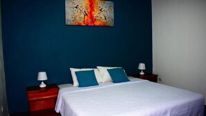 Un dormitorio con una cama, dos mesitas de noche y un cuadro en la pared.