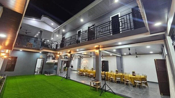 Un edificio de varios niveles con balcón, comedor interior y césped verde.