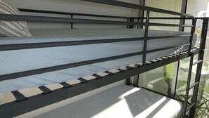 A bunk bed with metal railings, a window with a view of greenery, and a white pillow. - Charming Studio Steps from the Beach with Parking and Wi-Fi (La Grande-Motte)