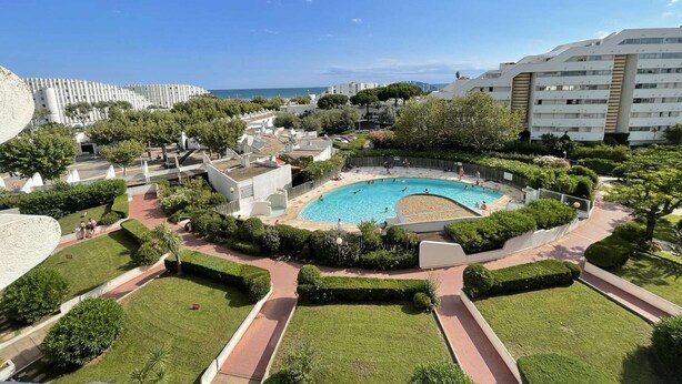Une piscine entourée de pelouses et d’allées bien entretenues, avec des bâtiments en arrière-plan.