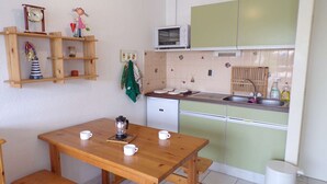A small kitchen with a wooden table, a microwave, and a sink. - Cozy Studio with Pool Access, Near Beach and Shops, Sleeps 4, Private Parking (La Grande-Motte)
