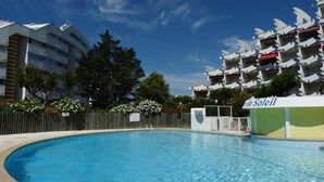 A swimming pool with a wooden fence, surrounded by buildings with balconies and a sign reading 'le Soleil'. - Cozy Studio with Pool Access, Near Beach and Shops, Sleeps 4, Private Parking (La Grande-Motte)