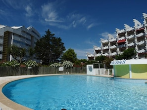 A swimming pool with a wooden fence, surrounded by buildings with balconies and a sign reading 'le Soleil'. - Cozy Studio with Pool Access, Near Beach and Shops, Sleeps 4, Private Parking (La Grande-Motte)