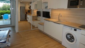 Una cucina moderna con lavatrice, forno a microonde e televisore.