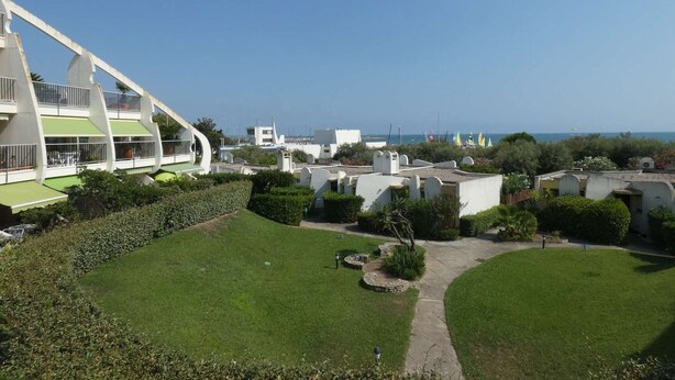 Un área residencial con un edificio de diseño curvo, un césped cuidado y vistas despejadas al mar.