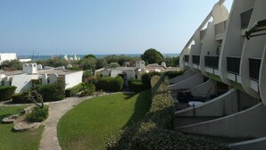 Un edificio moderno con balcones, vistas despejadas al mar y un jardín bien cuidado.