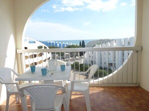 Ein Balkon mit Tisch und Stühlen, Blick auf eine Küstenlandschaft und ein Fliesenboden.