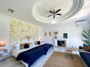 Une chambre à coucher comprenant un lit, un ventilateur de plafond, une cheminée, une petite table et un canapé.