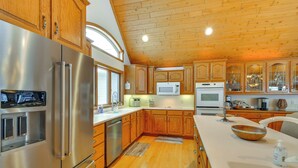 A kitchen with wooden cabinets, stainless steel appliances, and a wooden ceiling.