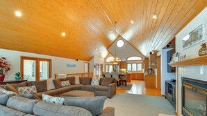 A spacious living area with a large sectional sofa, a fireplace, and a kitchen in the background.