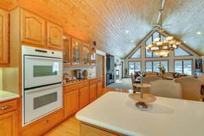 A kitchen with wooden cabinets, a white countertop, and a dining area with a chandelier.