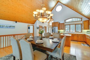 Una cocina amplia con armarios de madera, una isla grande y un comedor con mesa y sillas de madera.