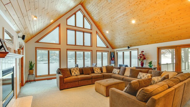 A spacious living room with a large sectional sofa, a fireplace, and large windows offering a view of the outdoors.