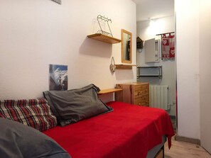 Ein kleines Schlafzimmer mit einem Bett, einem Schminktisch, einem Spiegel und einem Regal mit einem Fahrrad.