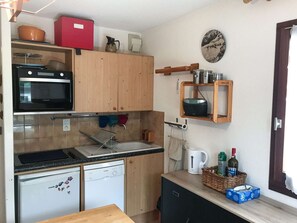 Eine kleine Küche mit Mikrowelle, Backofen, Spüle und einem kleinen Kühlschrank.