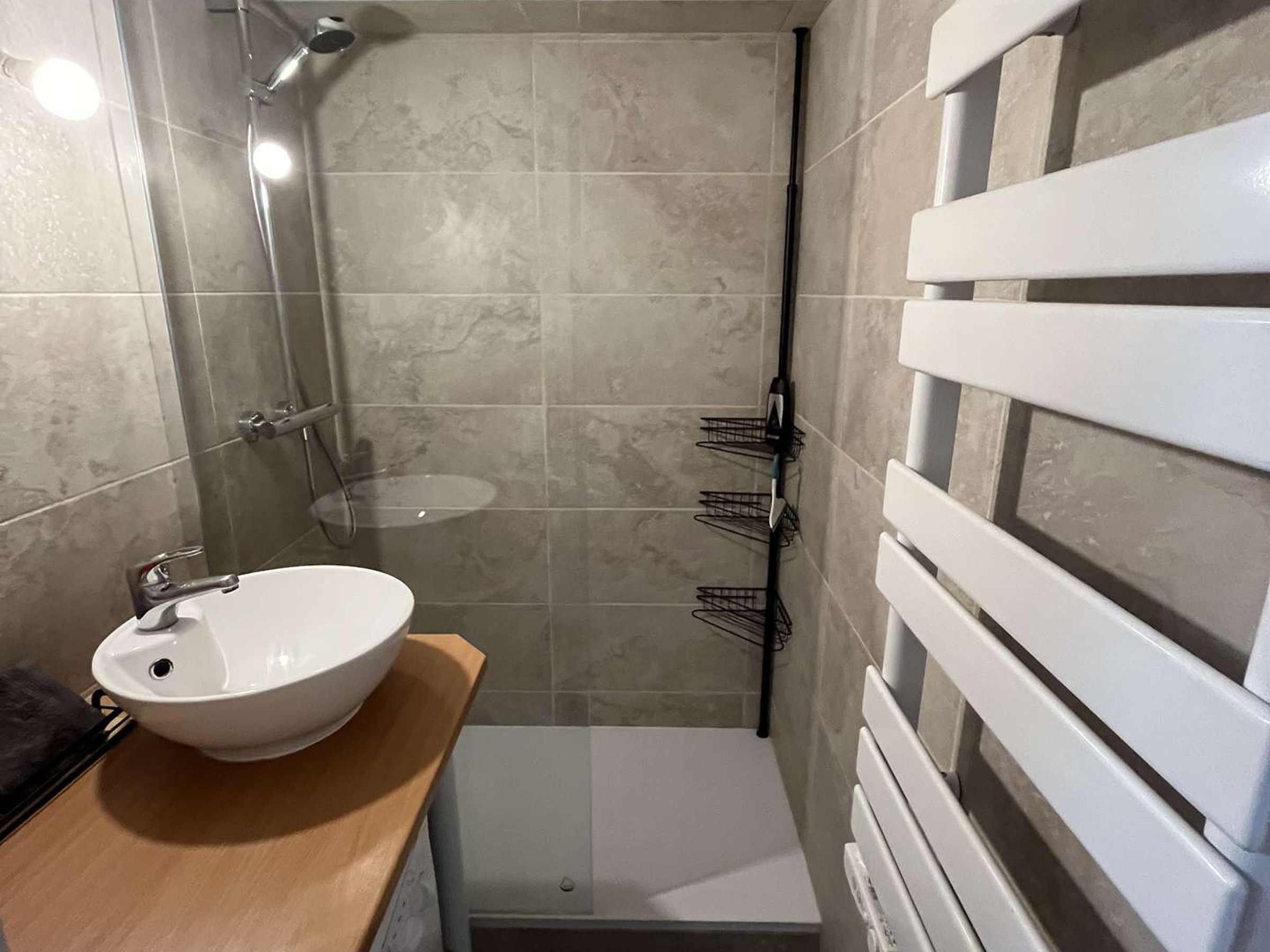Ein Badezimmer mit einem weißen Waschbecken, einer Dusche und einem Handtuchhalter.
