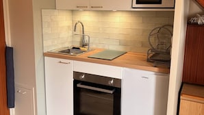 A compact kitchen with a built-in sink, a microwave, and an oven. - Cozy duplex near the sea - 4 guests (Merville-Franceville-Plage)