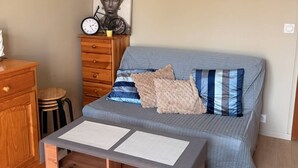 A bedroom with a bed, a dresser, a clock, and a painting on the wall. - Cozy duplex near the sea - 4 guests (Merville-Franceville-Plage)