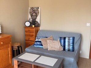 Ein Schlafzimmer mit Bett, Kommode, einer Uhr und einem Bild an der Wand.