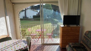 A balcony with a table, chairs, a sofa, and a TV. - Functional and bright studio, garden - 4 guests (Argelès-sur-Mer)