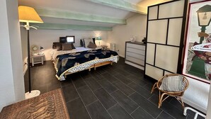 Een slaapkamer met een bed, nachtkastjes, een lamp, een dressoir, een stoel en uitzicht.