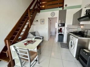A compact kitchen with a washing machine, a microwave, and a stove. - Apartment sea view, parking - 6 guests (Saint-Cyprien)