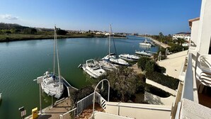 Een jachthaven met aangemeerde boten, een heldere lucht en een gebouw met balkon met uitzicht op het water.
