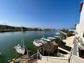A marina with boats docked, a clear sky, and a building with a balcony overlooking the water. - Apartment sea view, parking - 6 guests (Saint-Cyprien)