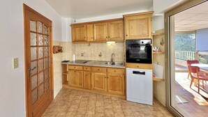 A compact kitchen with wooden cabinets, a built-in oven, and a dishwasher. - Terraced house, sea view - 6 guests (Ajaccio)