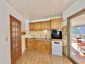 A compact kitchen with wooden cabinets, a built-in oven, and a dishwasher. - Terraced house, sea view - 6 guests (Ajaccio)