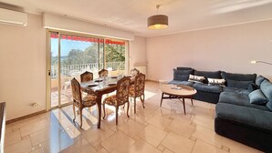 A living room with a dining area, a sofa, and a balcony with a view. - Terraced house, sea view - 6 guests (Ajaccio)