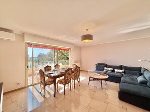 A living room with a dining area, a sofa, and a balcony with a view. - Terraced house, sea view - 6 guests (Ajaccio)