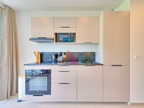 A modern kitchen with built-in appliances, a microwave, oven, and a coffee maker. - Studio suite in Anse Marcel - 2 guests (Saint-Martin)