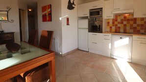 A kitchen with white cabinets, a microwave, oven, and dishwasher. There is a dining table with chairs. - Stunning AC Apartment for 6, Beach Access, Private Parking (Sète)