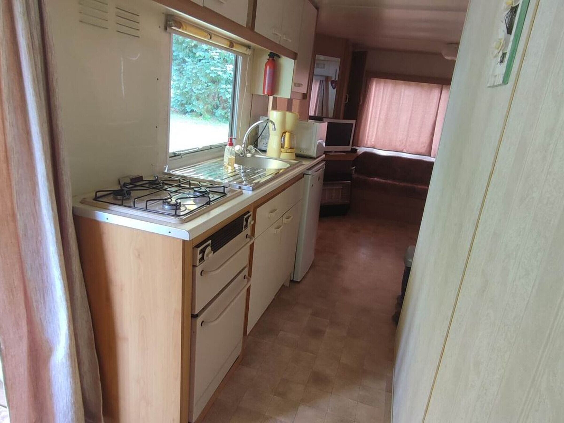 A compact kitchen with a gas stove, sink, and a small refrigerator.