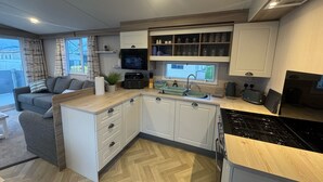 Een moderne keuken met witte kasten, een ingebouwde oven, een magnetron en een raam boven de gootsteen.