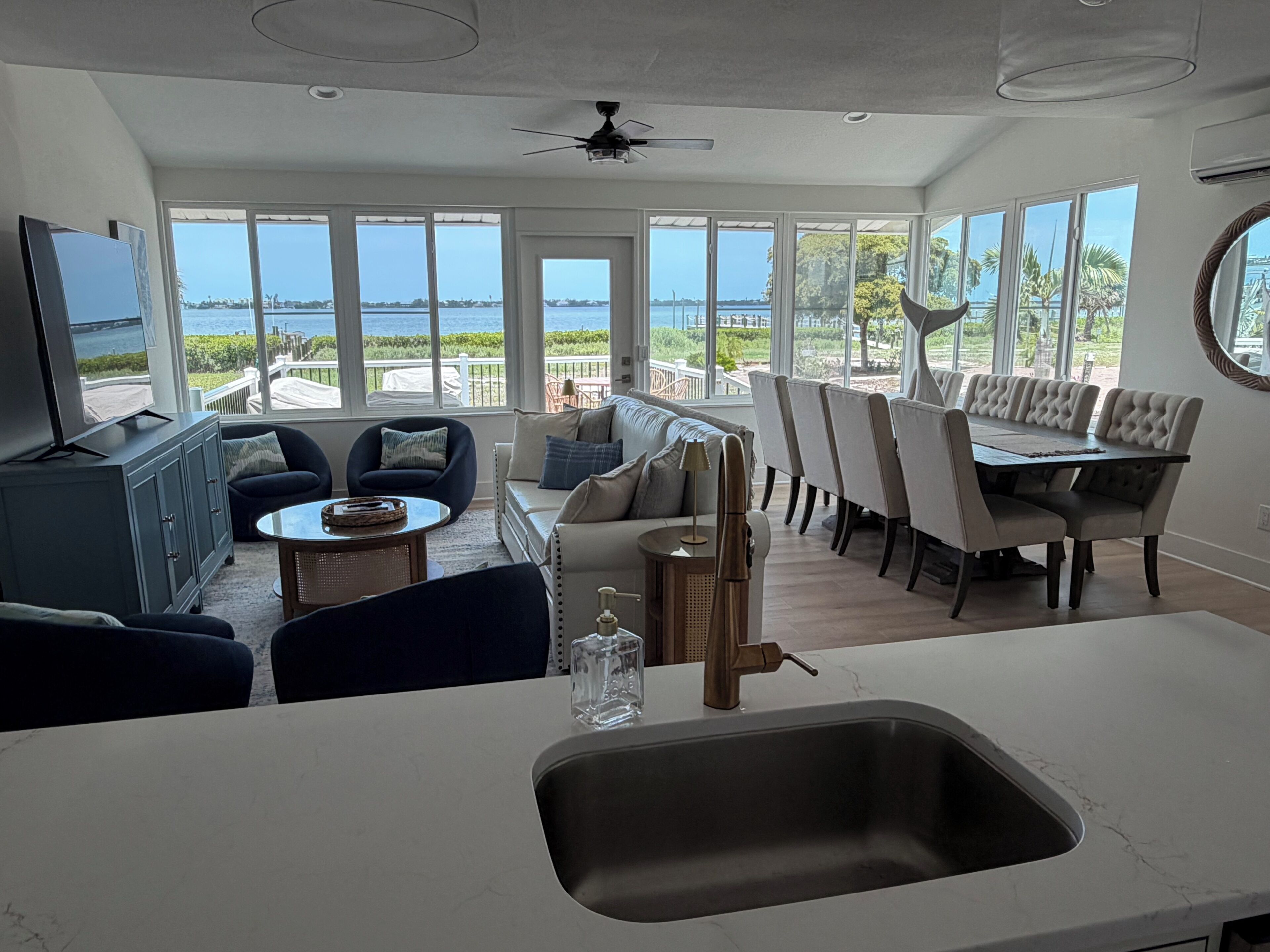 A spacious living area with a view of the sea, a dining table, and a kitchen with a sink.
