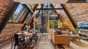 A cozy, wooden interior with a dining area, sofa, and a fireplace. - The Needles A-Frame Cabin! Grill/Hot tub/Pet friendly! (Flagstaff)