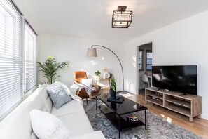 Una sala de estar moderna con un sofá, una mesa de centro, un televisor y una planta.