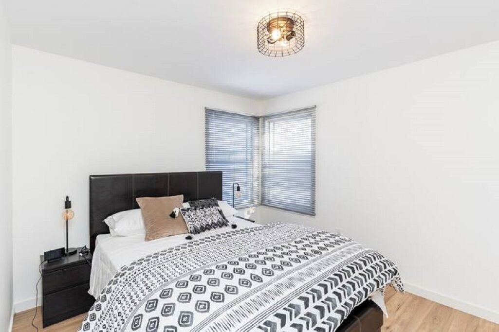 A bedroom with a bed, a nightstand, a lamp, and a ceiling light fixture.