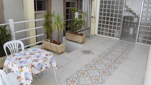 A balcony with a table, chairs, potted plants, and a patterned floor. - Sport Hostel Figueira da Foz (Figueira da Foz)