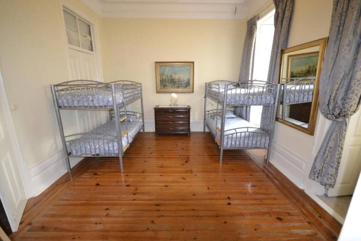 A room with bunk beds, a dresser, a framed picture, and a window with curtains.