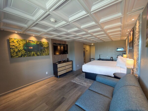 Une chambre d’hôtel moderne dotée d’un grand lit, d’un coin salon, d’une télévision à écran plat et d’un élément décoratif mural.