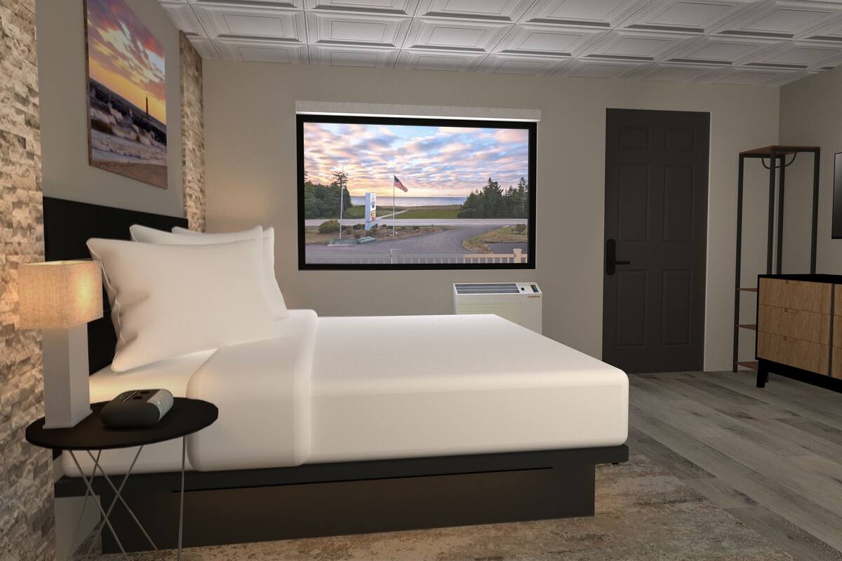 A modern bedroom with a bed, a TV, a desk, and a window with a view of a road and trees.
