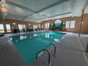 Ein Hallenbad mit Rettungsschwimmerstuhl, Rettungsboje und einem Wandgemälde von Wölfen.