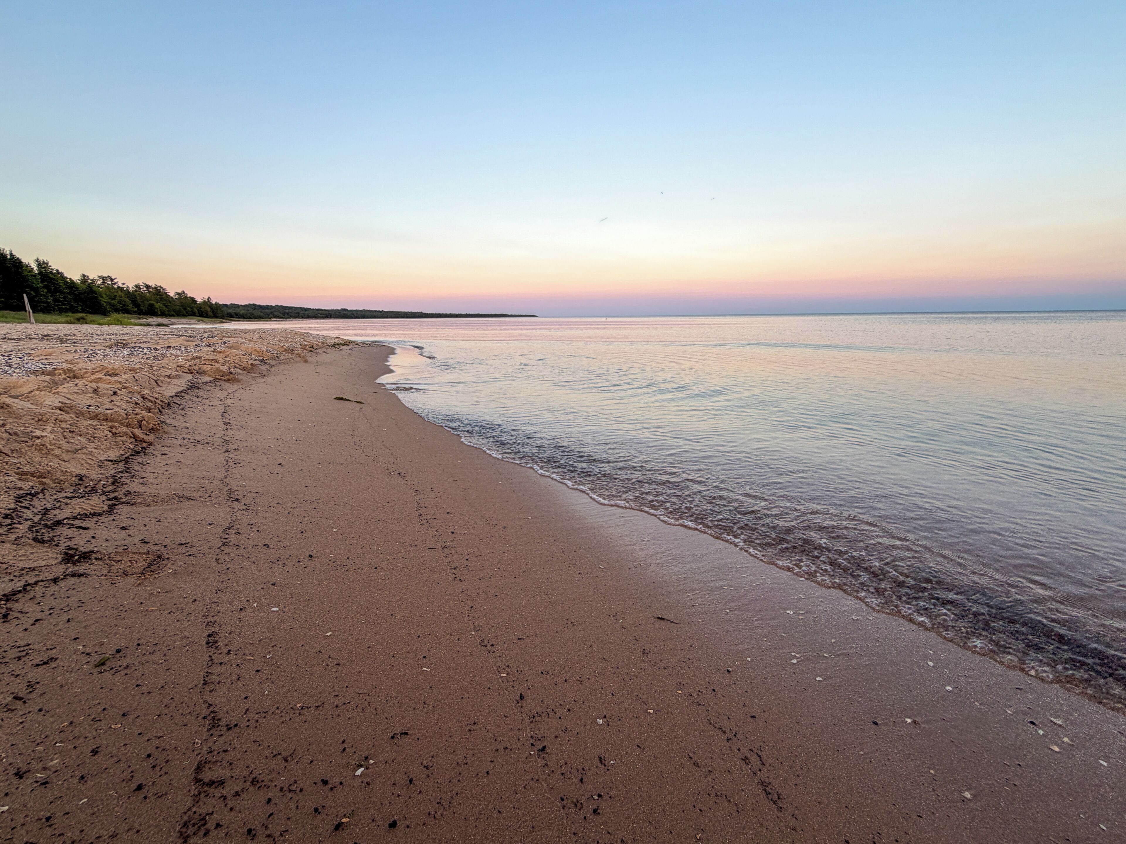 A beach with a wide sandy shore and calm water.