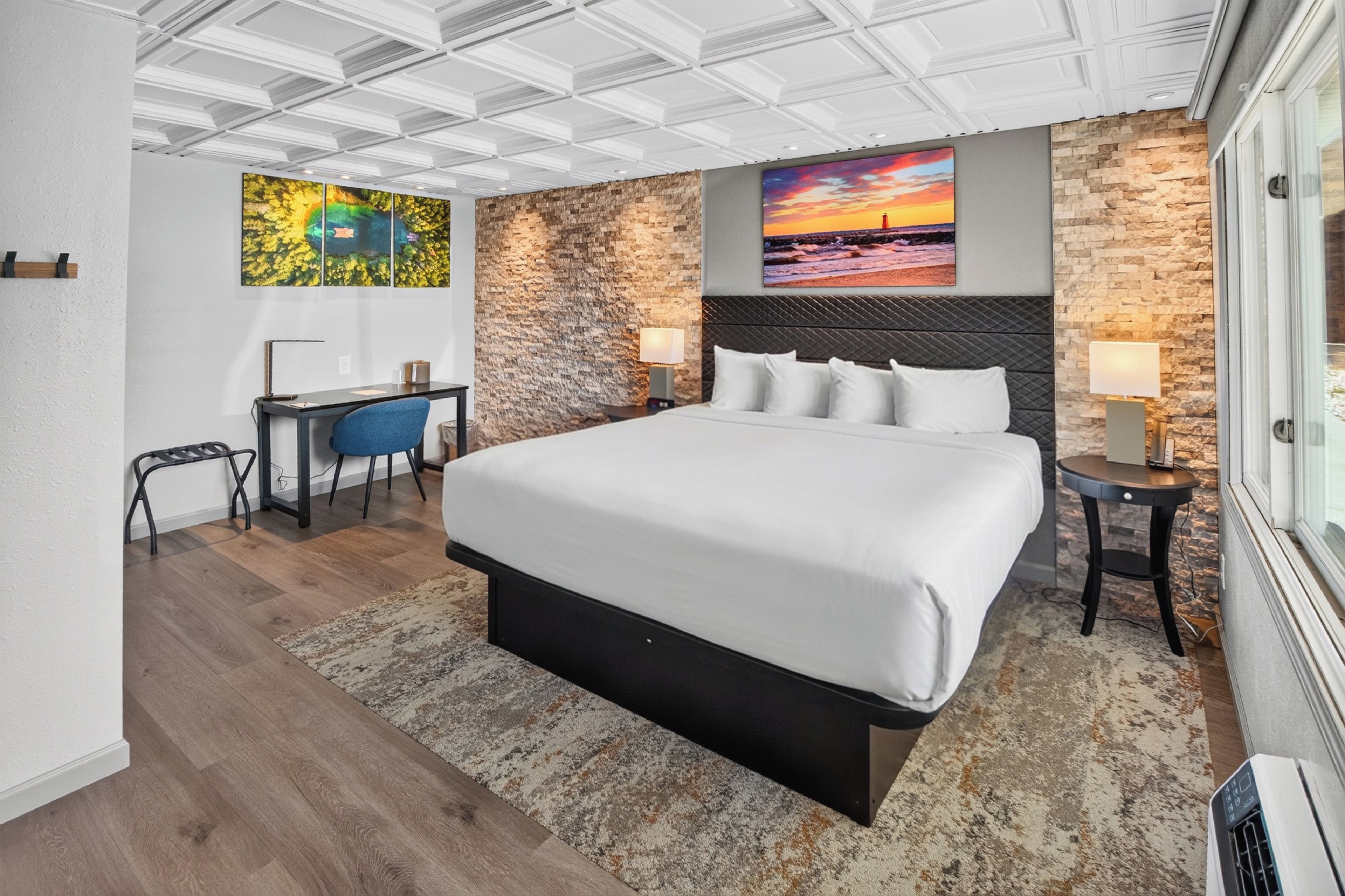 A modern hotel room with a large bed, a desk, and a view of the city.